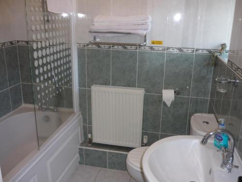 a bathroom with a sink and a toilet and a bath tub at De La Warr Guest House in Bexhill