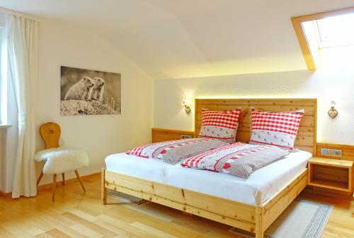 Schlafzimmer mit einem Holzbett mit roten und weißen Kissen in der Unterkunft Alpschatz Adlerhorst in Oberstdorf