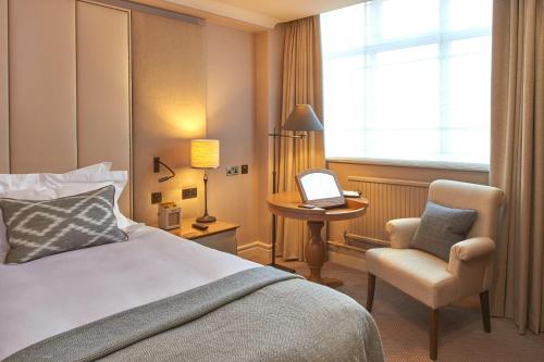 a hotel room with a bed and a chair and a laptop at The Milner York in York