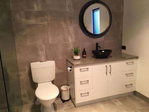 a bathroom with a toilet and a mirror at Apostle Hideaway - Central Port Campbell in Port Campbell