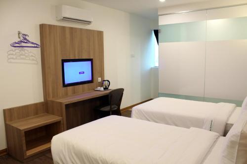 a hotel room with two beds and a television at Greencity Hotel in Sungai Petani