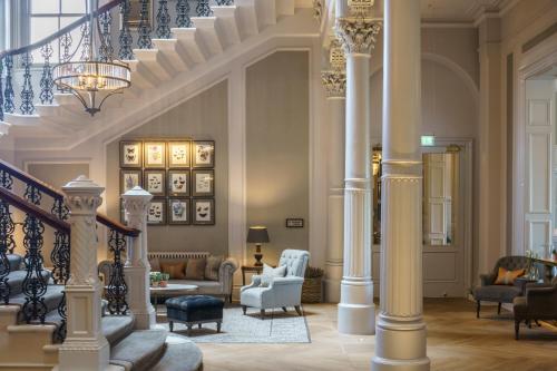 a lobby with a staircase with chairs and tables at The Milner York in York