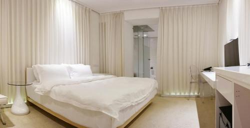 a white bedroom with a bed with white sheets at The Tree House in Kaohsiung