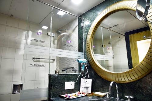 a bathroom with a mirror and a sink at The Senator Hotel in Kolkata