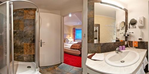 a bathroom with a sink and a shower and a bedroom at Smileys Kinderhotel in Trebesing