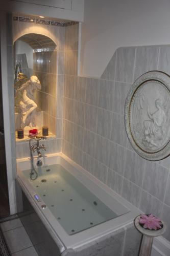 a bath tub in a bathroom with a painting on the wall at Chateau de la Chapelle des Bois in Fleurie