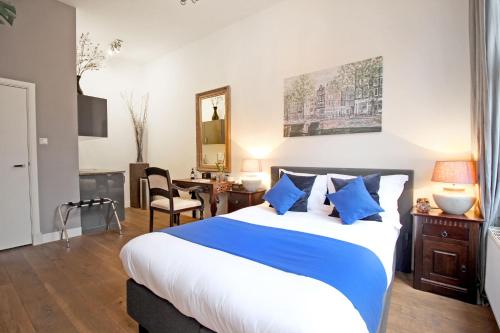 a bedroom with a large bed with blue pillows at New monumental garden view Studio in Amsterdam