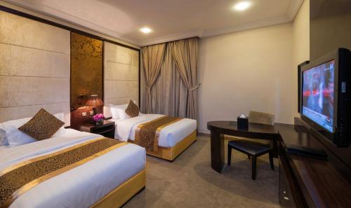 a hotel room with two beds and a flat screen tv at Boudl Taif in Taif