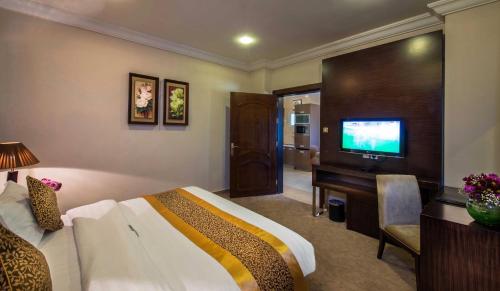 a hotel room with a bed and a flat screen tv at Boudl Taif in Taif