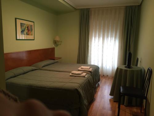 a bedroom with a bed and a table with a television at Hotel Benlloch in Salas de los Infantes
