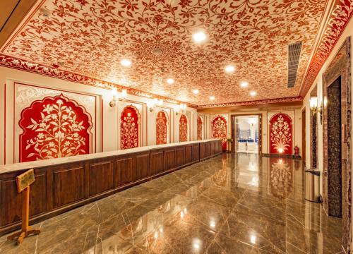 a large hall with red and gold wallpaper at Umaid Haveli-A Heritage Style Hotel & Resort in Jaipur