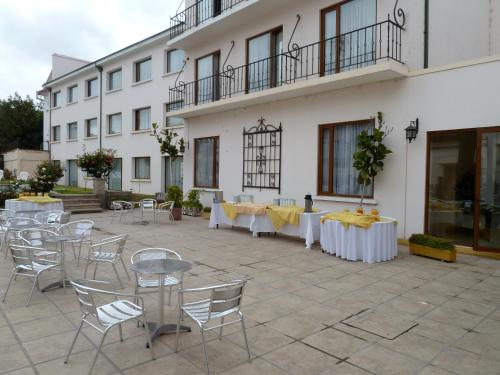 a row of tables with chairs and umbrellas in front of a building at Hotel Francisco De Aguirre in La Serena