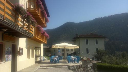 a patio with tables and an umbrella in front of a building at Hotel Serenella in Canale San Bovo
