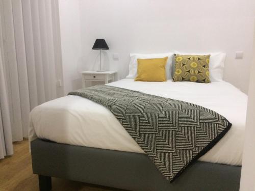 アヴェイロにあるAveiro White Studiosのベッドルーム(白い大型ベッド、黄色い枕付)