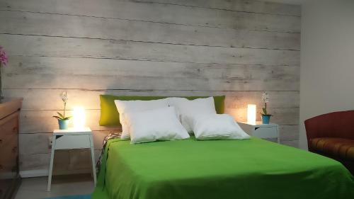 1 cama verde con 2 almohadas blancas y 2 mesas en Like Home Gedera, en Gedera