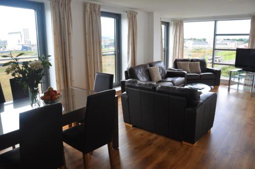 a living room with couches and a table and chairs at Ocean Serviced Apartments in Edinburgh