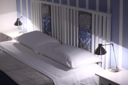 a bedroom with a white bed with two lamps at Door Eight in Il-Furjana