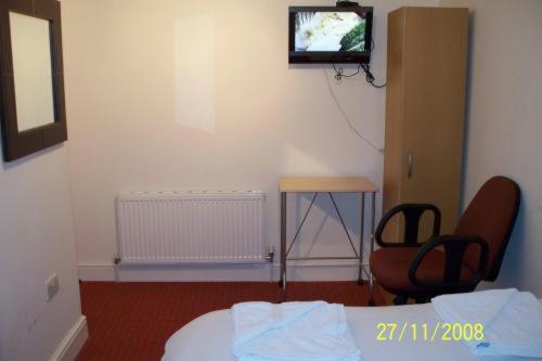 a room with a bed and a chair and a television at Citystay Hotel in London