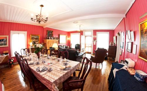 a dining room with a table in a room with red walls at Maison Hovington in Tadoussac
