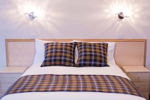 a bed with two plaid pillows on top of it at Leys Hotel in Aberdeen