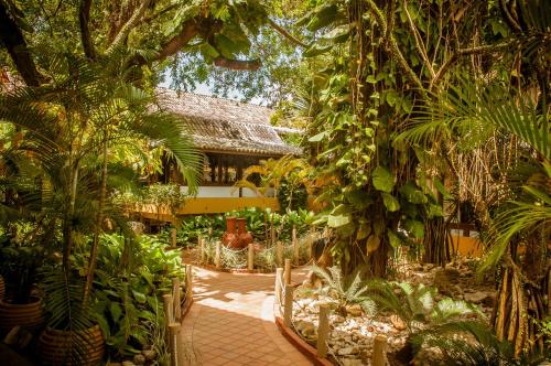 einen Garten mit Bäumen und Pflanzen und ein Gebäude in der Unterkunft Casa Blanca Park Hotel in Porto Seguro