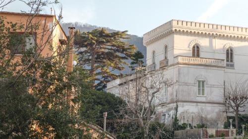 an old white building with a tree in the foreground at Villa Manning Relais in Sorrento