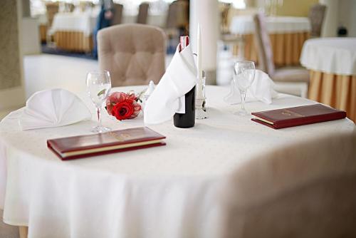 a white table with glasses and a bottle of wine at Hotel Malwa in Ostrów Wielkopolski