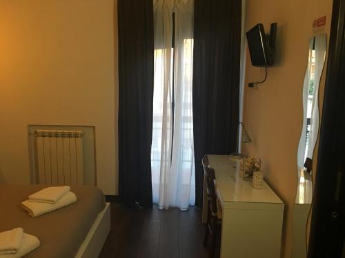 um quarto com uma cama, uma secretária e uma televisão em Almi Rooms em Roma