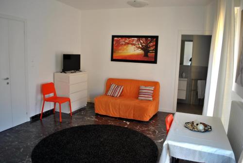een woonkamer met een oranje stoel en een bank bij Agli Ospedali in Padua