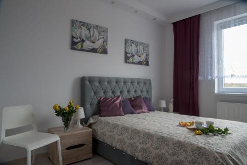 um quarto com uma cama com almofadas roxas e uma cadeira em Apartament Piła Równa em Piła