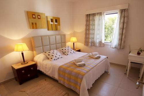 a bedroom with a bed with two lamps and a window at The Love Nest in Pissouri