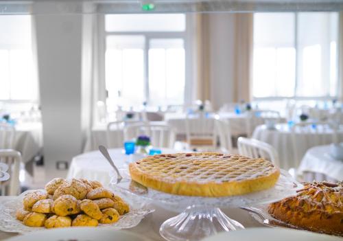 a table with a pie and some pastries on plates at Hotel Riviera in Bellaria-Igea Marina