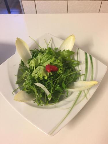 une assiette blanche avec une salade sur une table dans l'établissement Le Relais des Mayens de Chamoson, à Ovronnaz