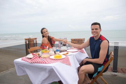 un homme et une femme assis à une table dans l'établissement Pousada e Restaurante Altas Horas Beach, à Itapipoca