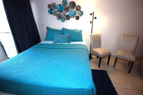 a bedroom with a blue bed and two chairs at 1004 BLUE OASIS in Honolulu