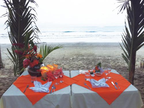 a table on the beach with flowers and wine glasses at Hotel Puerto Gaviota in Tonsupa