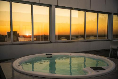 uma banheira de hidromassagem num quarto com vista para o pôr-do-sol em Plaza São Rafael Hotel em Porto Alegre