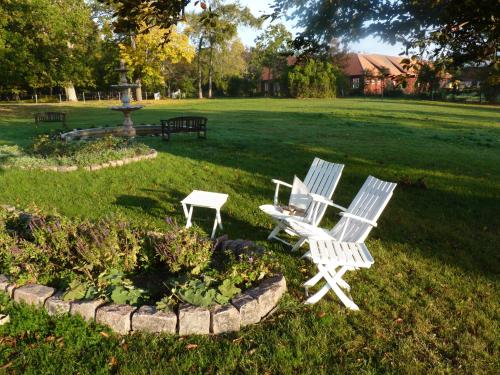 twee witte stoelen en een tafel in een park bij Nygårds Herrgård Bed & Breakfast in Mönsterås