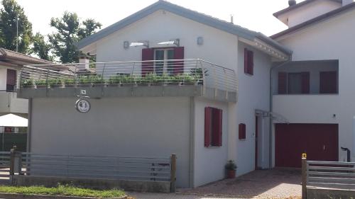 a white house with a balcony with plants on it at B&B Nuova Ostiglia in Quinto di Treviso