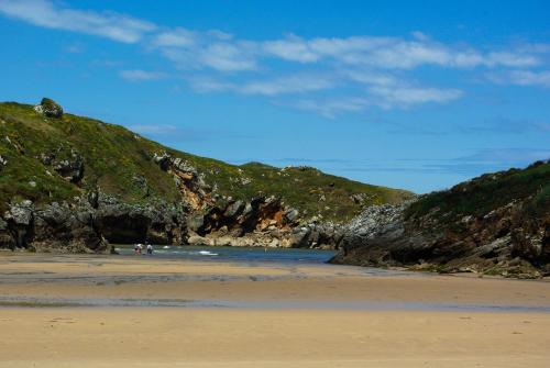 a beach with a group of people standing on the sand at Casa El Pilpayu in poo de Llanes