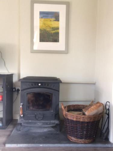 a fireplace with a basket and a picture on the wall at The Groom's Cottage in Navan