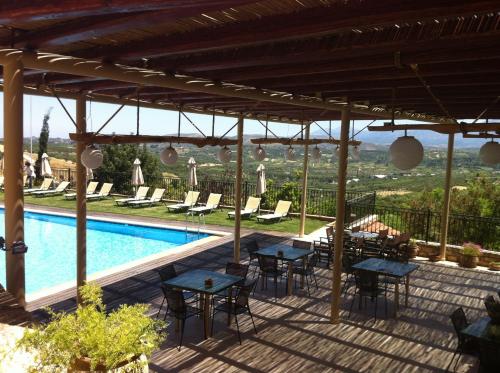 a patio with tables and chairs next to a swimming pool at Katalagari Country Suites in Archanes