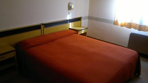 a bedroom with a orange bed with a window at Hotel Centrale in Argenta