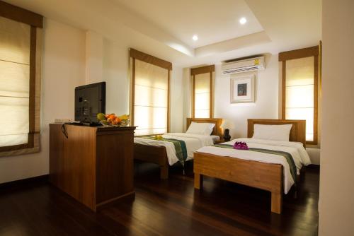 um quarto de hotel com duas camas e uma televisão em Thaihome Resort em Ban Bang Muang