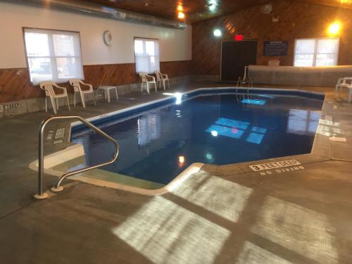 a large swimming pool in a building with chairs around it at Villager Motel & Glen Manor Estate in Watkins Glen