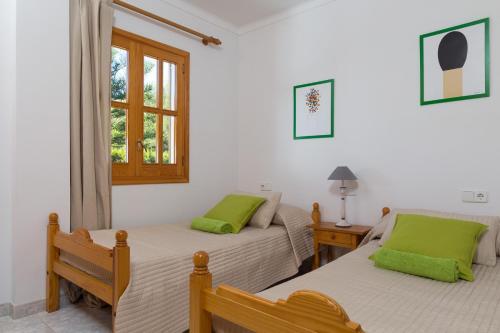 two beds in a room with two green pillows at Mar Blava House in Playa de Muro