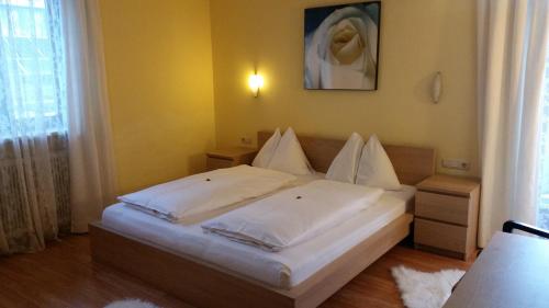 a bedroom with a bed with white sheets at Sportpension Sonnhof in Taxenbach