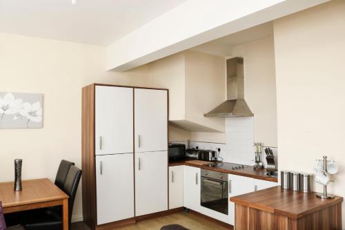 uma cozinha com armários brancos e uma mesa de madeira em Parks Nest 5 em Hull