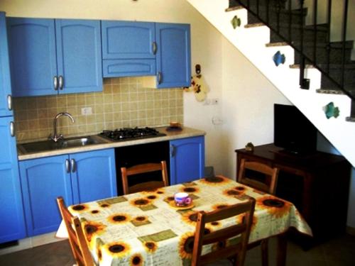 una cocina con armarios azules y una mesa con sillas en I Villini di Baia Delle Mimose en Badesi