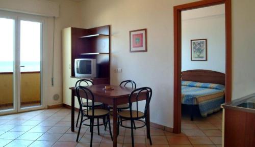 Residence Carioca في ريميني: غرفة مع طاولة وكراسي وغرفة نوم